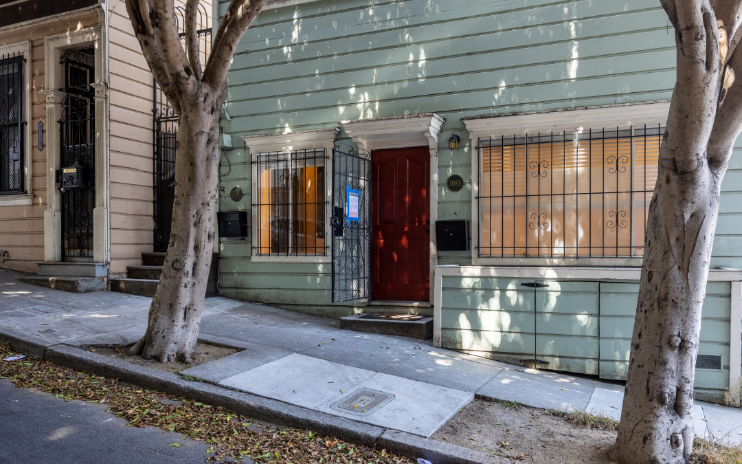 Lily - street view of a teal blue house with a red door