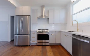 Modern San Francisco kitchen remodel with white shaker cabinetry, stainless appliances, brass hardware, and warm wood flooring