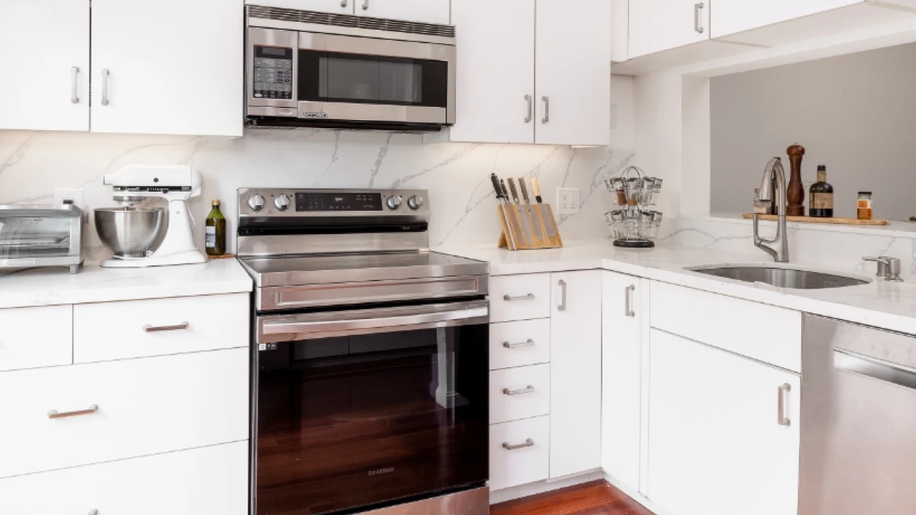 Bay Area kitchen renovation featuring white shaker cabinets, stainless range and integrated appliances with marble-look backsplash