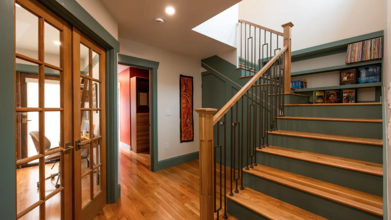 Modern San Francisco home stair hall with wood treads, green millwork, glass-paneled doors, and custom metal railing detail