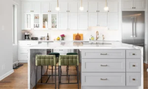 sleek remodeled kitchen with white cabinetry and green upholstered bar stools at waterfall island in Bay Area home