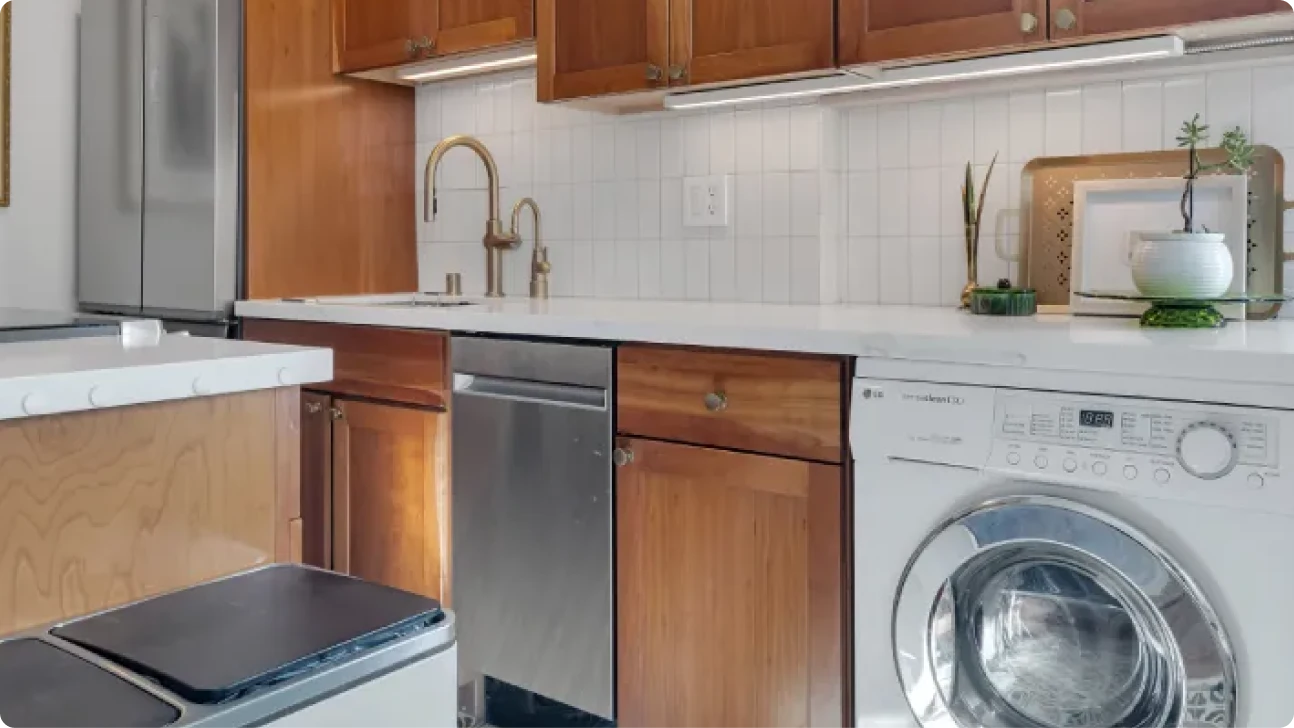 Modern San Francisco kitchen remodel with warm wood cabinetry, integrated washer, brass faucet, white countertops, and green patterned tile flooring