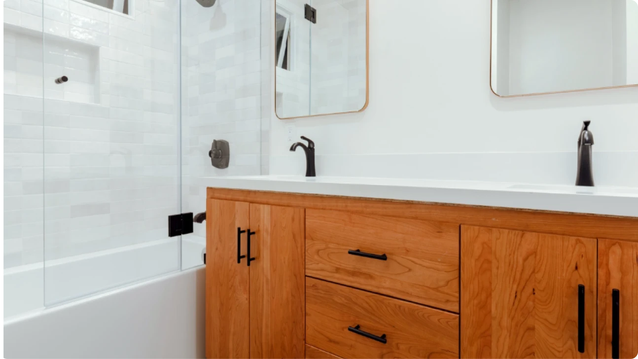 Modern Bay Area bathroom renovation with warm wood vanity, white quartz countertop, matte black fixtures, and glass-enclosed tub shower