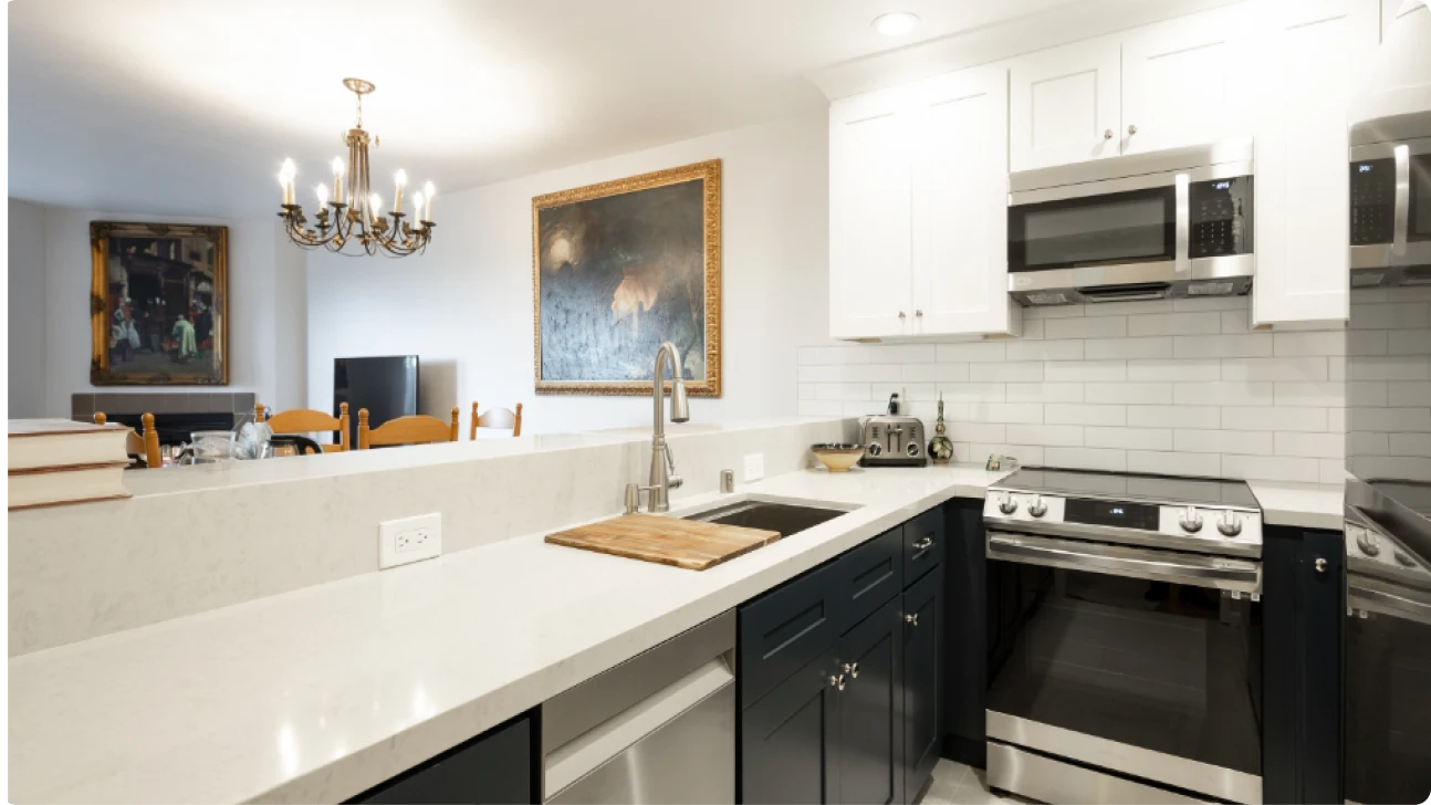 Modern San Francisco kitchen remodel with quartz countertops, navy base cabinets, stainless steel appliances, and open flow to dining area with chandelier and artwork