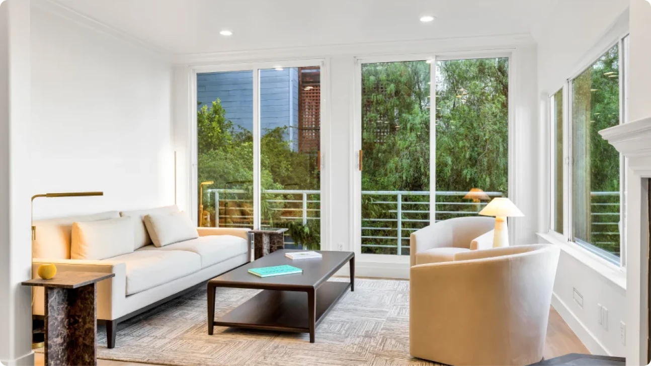 Bright Bay Area living room renovation with expansive windows, neutral seating, and indoor-outdoor connection overlooking greenery
