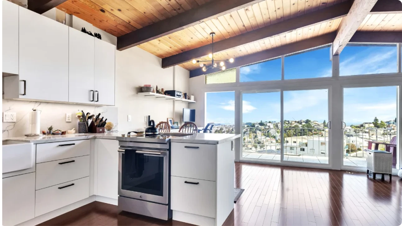 Bright Bay Area kitchen renovation with vaulted wood ceilings, white cabinetry, and large windows showcasing city views
