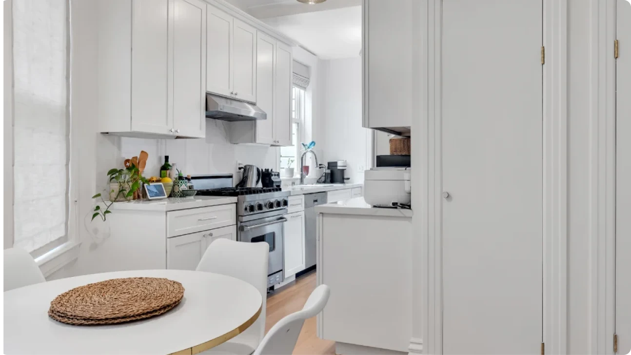 Bright Bay Area kitchen renovation featuring round dining table, white cabinetry, quartz counters, and compact nook integrated into a galley layout