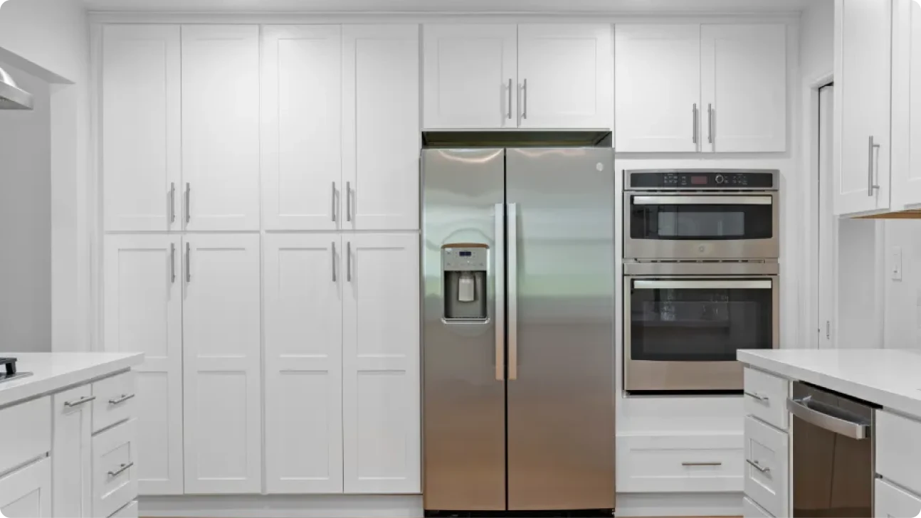 Clean contemporary kitchen detail showing tall white cabinetry, built-in oven, fridge, and sleek quartz surfaces in Bay Area home