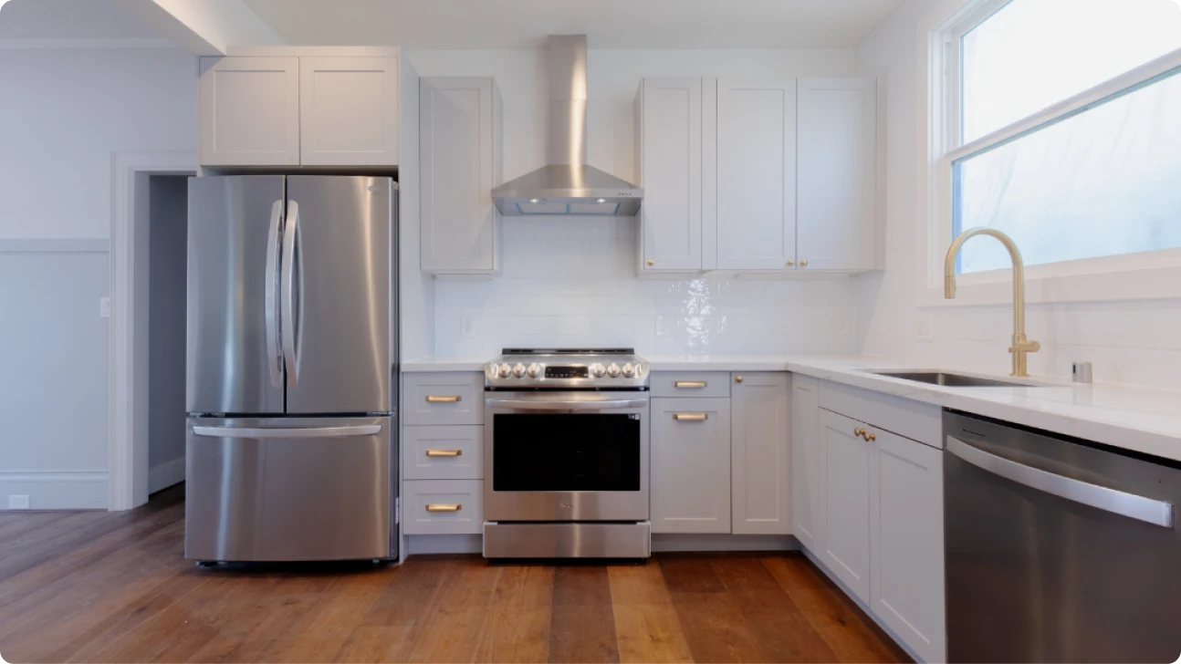 Modern San Francisco kitchen remodel with white shaker cabinets, stainless steel appliances, brass hardware, and warm wood flooring