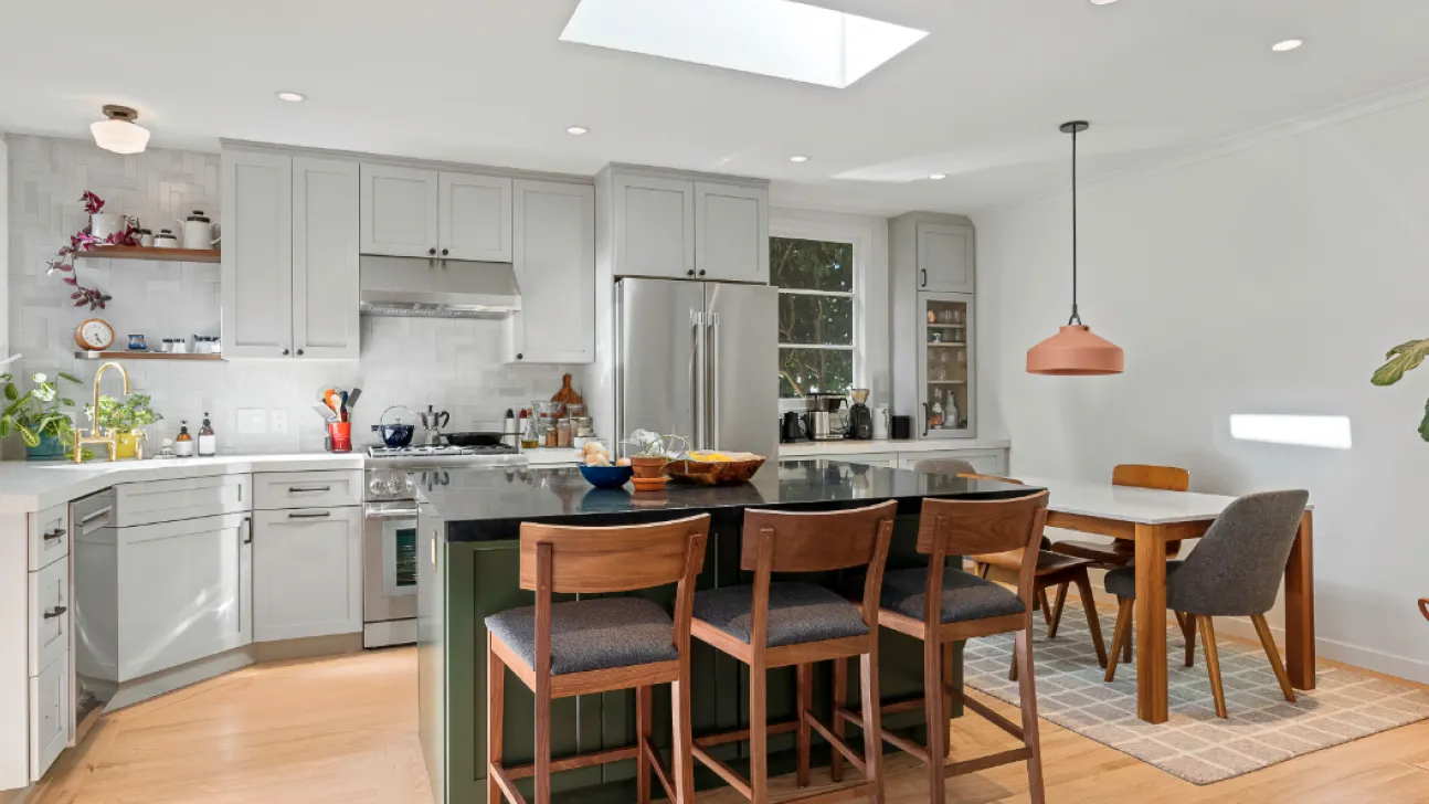 Bright modern San Francisco kitchen with central island, skylight, wood flooring, gray cabinets, and casual dining area after remodel