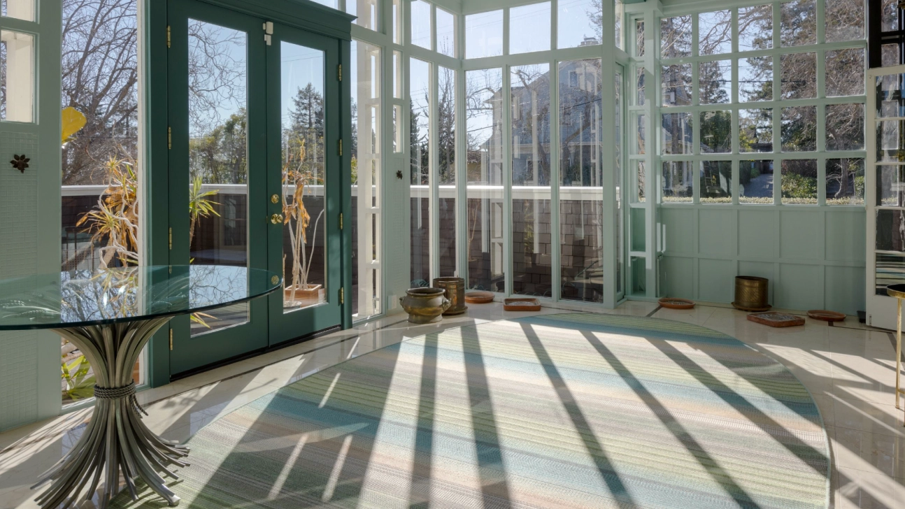 Bright San Francisco sunroom remodel with teal trim, glass walls, French doors, and skylit indoor-outdoor living space