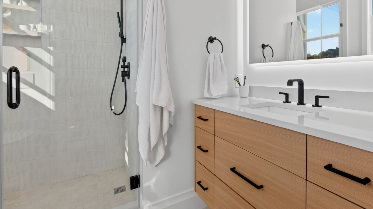 Contemporary Bay Area bathroom remodel with light wood vanity, black fixtures, and bright shower enclosure in San Francisco home.