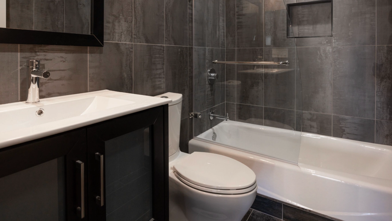 Modern San Francisco bathroom remodel with dark large-format tile, glass shower enclosure, integrated tub, and sleek vanity with chrome fixtures