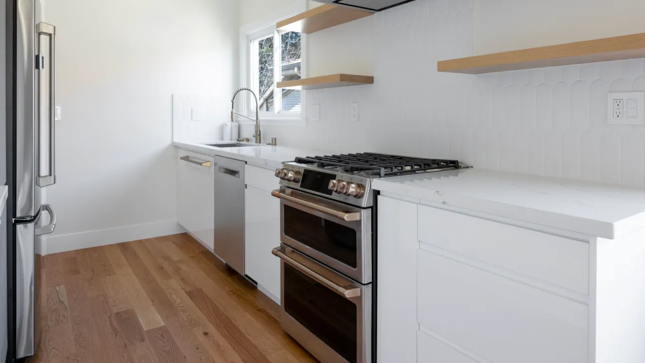 Modern San Francisco kitchen remodel with white shaker cabinets, quartz countertops, full-height textured tile backsplash, and stainless steel range in a bright galley layout