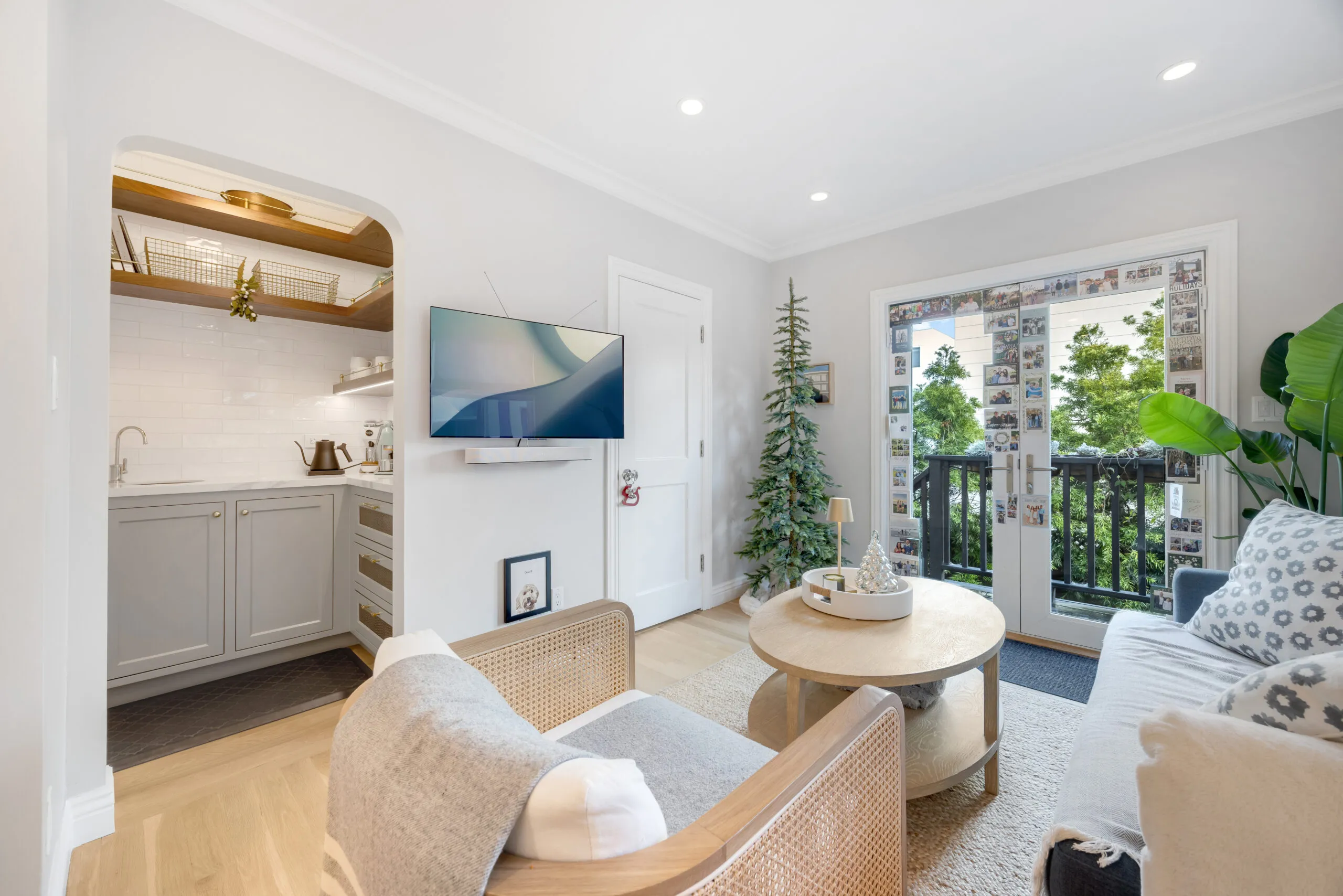 Bright living room with light wood floors, built-in wet bar and balcony doors in modern San Francisco remodel with cozy lounge seating