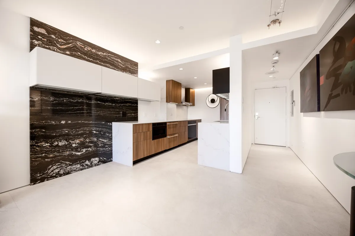 Modern kitchen remodel with dramatic natural stone slab backsplash and walnut cabinetry.