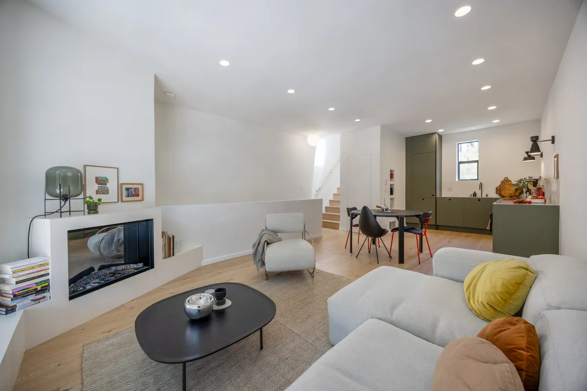Renovated open-concept living room with fireplace, dining area, and kitchen completed by Mission Home Remodeling.