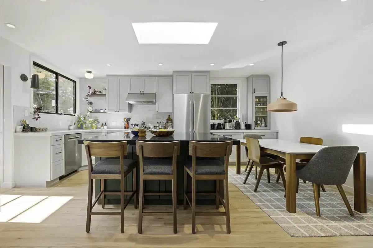 Completed open-concept kitchen remodel with white cabinetry, kitchen island, dining area, and wood flooring