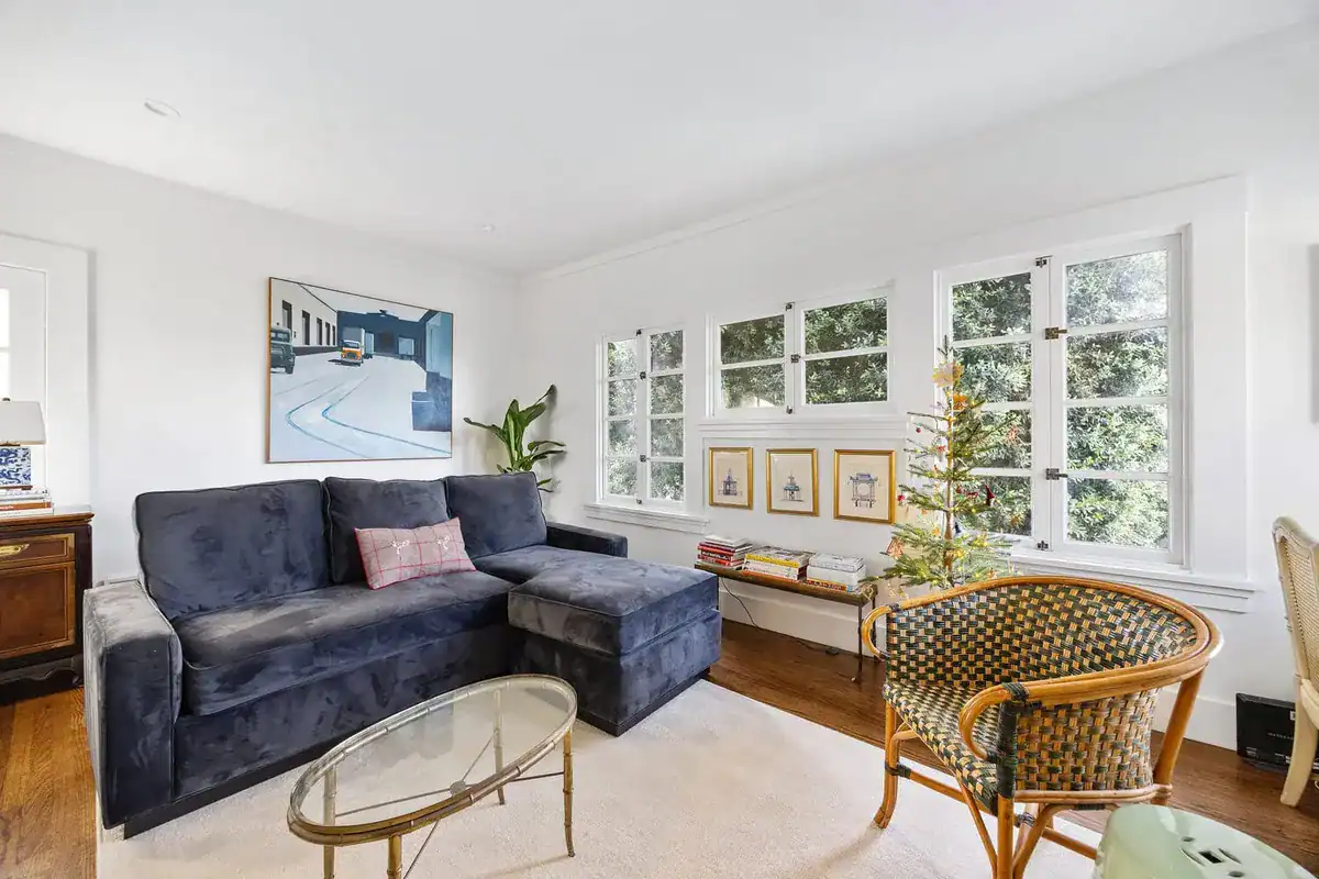 Bright living room with hardwood floors, a wall of white casement windows, and a sectional sofa