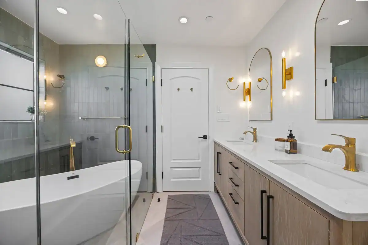 Remodeled bathroom with a freestanding tub inside a glass wet room enclosure, white oak double vanity, and brass fixtures